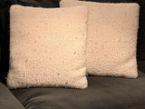 two white pillows sitting on top of a couch next to each other