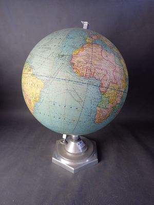 un petit globe terrestre posé sur un socle métallique, sur fond noir