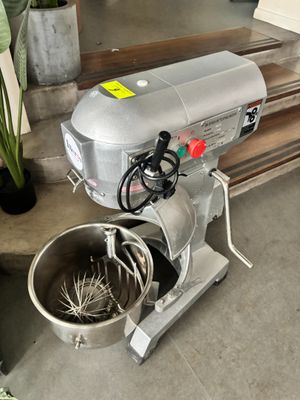 un mixeur argenté posé par terre à côté d'une plante en pot