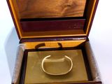 a gold ring in a wooden box on a white surface