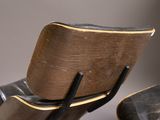 a wooden chair and ottoman with a black leather seat