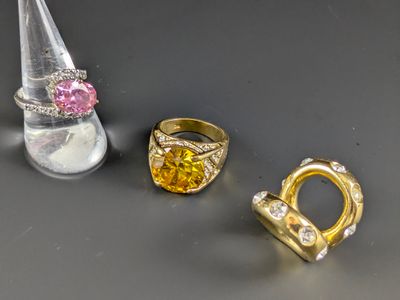 trois bagues et une bague sertie d'un diamant rose posée sur une table