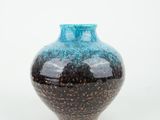 un vase bleu et noir posé sur une surface blanche