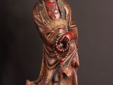 statue of a person holding a bowl of fruit next to an apple