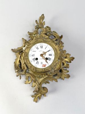 a gold clock on a white wall with a white background