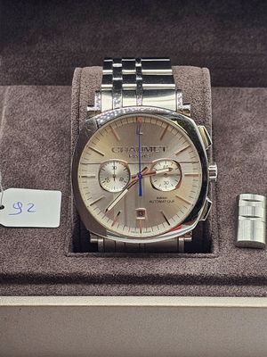 une montre et un briquet dans une boîte sur laquelle est accrochée une étiquette