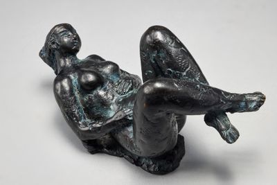 sculpture of a woman laying on her back on a white surface