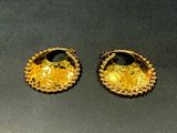 two pairs of gold earrings on a black surface