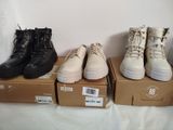several pairs of shoes are lined up on boxes on a bed