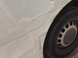 une camionnette blanche avec un pneu crevé, garée sur le bord de la route