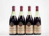 quatre bouteilles de vin sont alignées sur une surface blanche