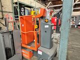 Une pince orange est entreposée dans un entrepôt avec d'autres équipements industriels