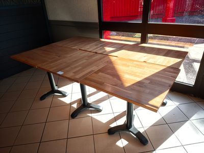 une table en bois avec deux pieds noirs, placée devant une fenêtre