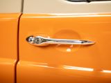 a close up of a car door handle on an orange car