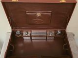 an open brown suitcase sitting on top of a table next to a wall