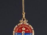a close up of a gold necklace with a medal on it