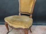 an old chair with a yellow upholstered seat on a carpeted floor