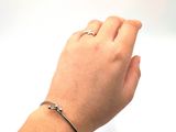 a woman ' s hand with a silver bracelet on it