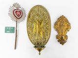 a gold statue of the virgin of guadalupe next to a wand and a plaque