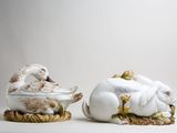 pair of porcelain figurines of a sleeping duck and a sleeping duck