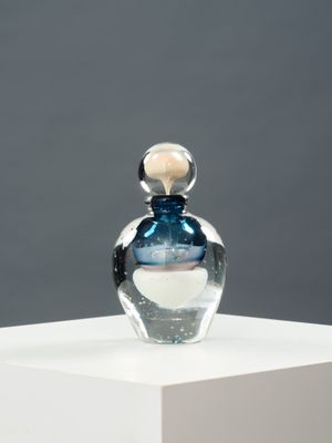 une photo d'un flacon de parfum posé sur une table blanche