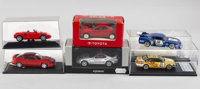 quatre modèles différents de petites voitures exposés dans des vitrines posées sur une surface blanche