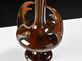 a brown glass vase with a brown handle on a white table