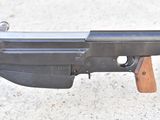 a gun with a wooden handle on a concrete surface