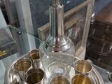 a silver tray with silver cups and a bottle on it
