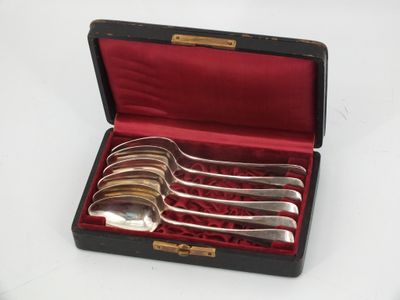 four silver spoons in a black case on a table