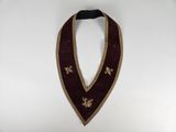 a close up of a red and gold collar on a white background