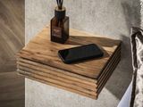 un téléphone portable posé sur une étagère en bois, à côté d'un vase contenant des roseaux
