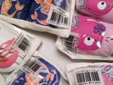 several pairs of children ' s slippers in plastic bags on a table