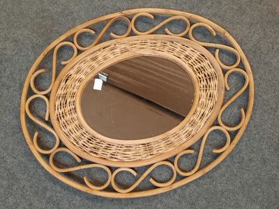 un miroir en osier posé par terre près d'une porte