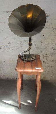 une petite table en bois sur laquelle trône un vieux gramophone