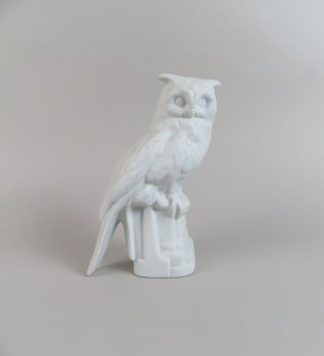 une figurine blanche représentant un hibou perché sur une souche d'arbre