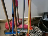 several brooms and mops are sitting on the floor next to a bucket