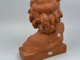 statue of a child with curly hair sitting on a wooden base