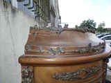 une commode en bois ornée de sculptures élaborées, placée devant un bâtiment