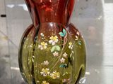 un vase en verre orné de fleurs, posé sur une étagère en verre