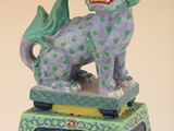 figurine chinoise représentant un chien violet et vert sur un socle vert