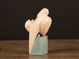 a ceramic sculpture of a bird sitting on top of a wooden table