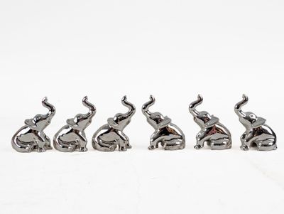 four silver elephant figurines sitting in a row on a white surface