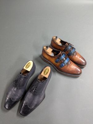 two pairs of men ' s shoes sitting on a table next to each other