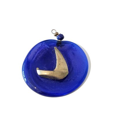 a blue glass ornament with a gold sailboat on it