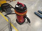 a red and black vacuum sitting on the floor in a warehouse