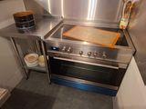 une cuisinière en acier inoxydable dans une cuisine où se trouve une planche à découper sur le plan de travail