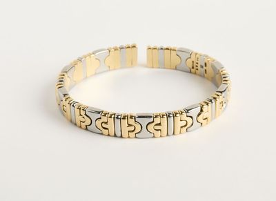 un gros plan d'un bracelet en argent et en or posé sur une surface blanche