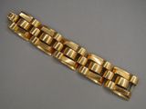 gros plan d'un bracelet en or sur une surface grise