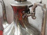 une théière en argent posée sur une table rouge
